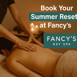 A person receives a relaxing back massage in a softly lit spa room with glowing candles. Overlay text reads “Book Your Summer Reset at Fancy’s” alongside the Fancy’s Day Spa logo.